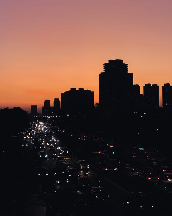 Urban community at dusk with buildings and traffic.
